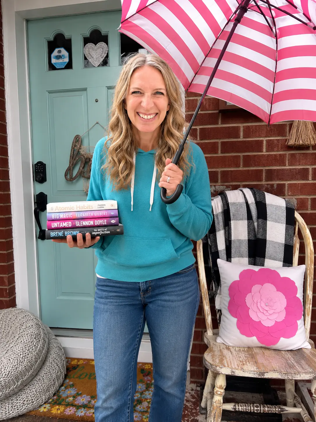 Lizzy with an umbrella and a stack of books on her front porch.