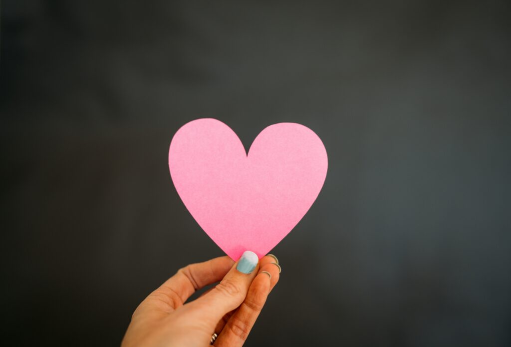 One single heart is held by a woman's hand.